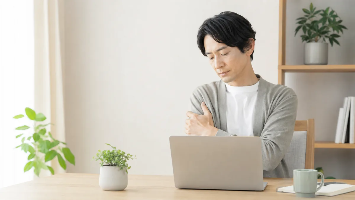 パソコン作業のあと、腕の重だるさを気にする男性